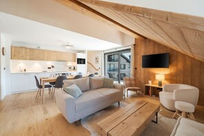 A modern living space with a wooden ceiling, a sofa, a dining table, and a TV mounted on the wall. - 4 beds duplex | Close ski lifts | Central | Views (Saint-Gervais-les-Bains)