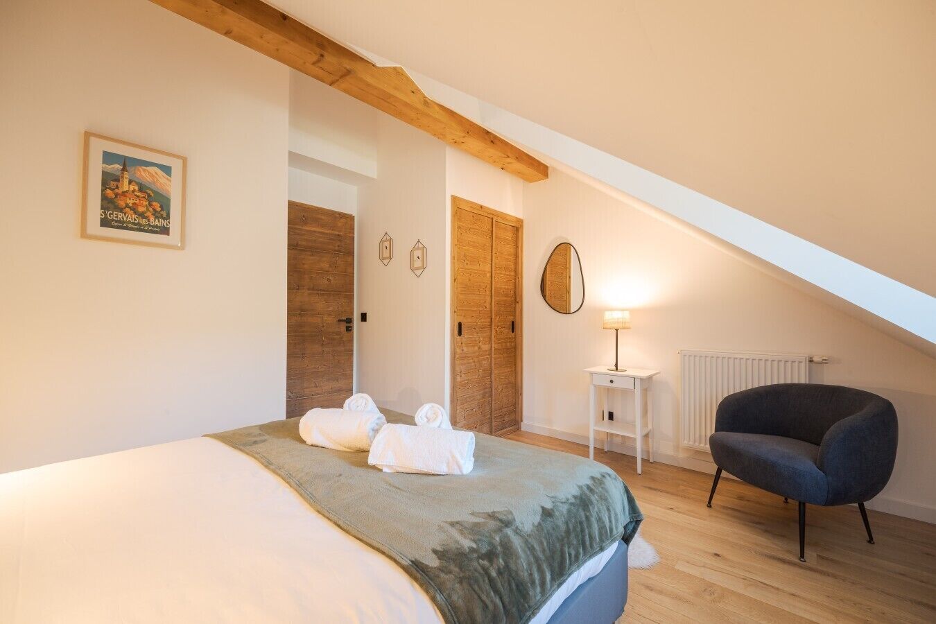 Une chambre à coucher avec un lit, deux portes en bois, une lampe et une chaise.