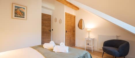 Een slaapkamer met een bed, twee houten deuren, een lamp en een stoel.