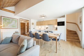 A modern interior with a dining area, kitchen, and staircase. - 4 beds duplex | Close ski lifts | Central | Views (Saint-Gervais-les-Bains)
