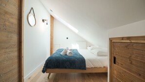 Een kamer met een bed, houten wanden, een dakvenster en een spiegel.