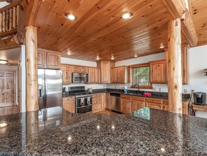 Una cocina amplia con gabinetes de madera, un refrigerador de acero inoxidable, un microondas, una estufa y encimeras de granito.