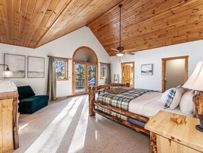 Une pièce avec un plafond en bois, un lit avec un cadre en bois, un bureau et une chaise.