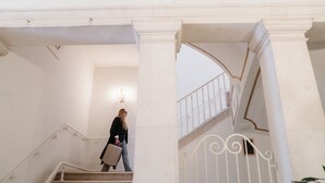Un magnifique escalier à colonnes blanches, surmonté d’un lustre, menant à un niveau supérieur.