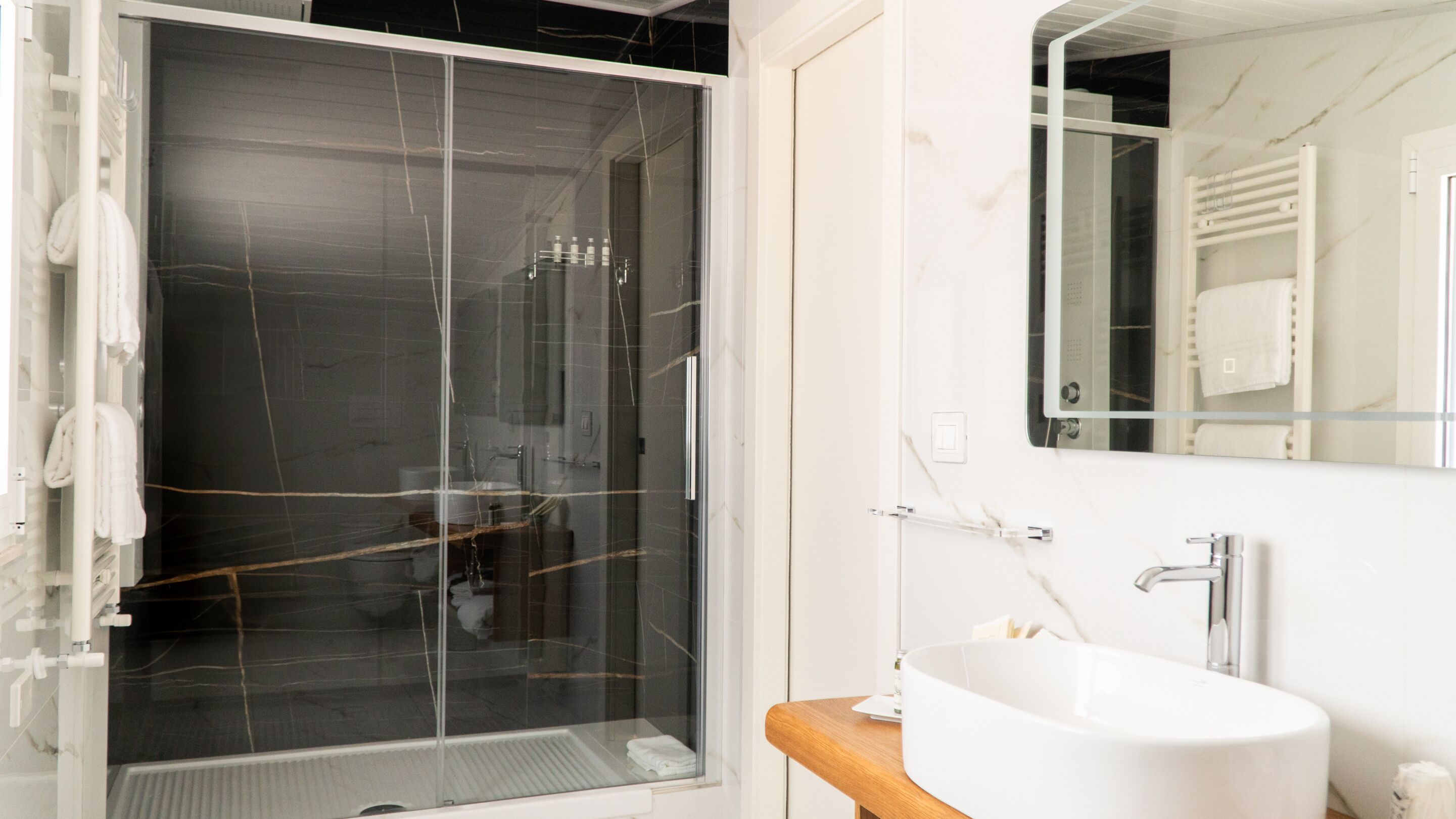 A modern bathroom with a glass-enclosed shower, a white sink, and a mirror above the sink.