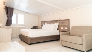 Une chambre à coucher comprenant un lit, une chaise, une table de chevet, un radiateur et une fenêtre avec des rideaux.