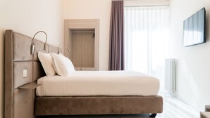 Une chambre à coucher avec un lit, des lampes de chevet, une armoire et un téléviseur.