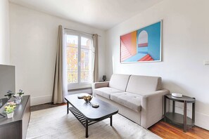 Ein Wohnzimmer mit einer Couch, einem Couchtisch, einem Beistelltisch und einem Bild an der Wand.