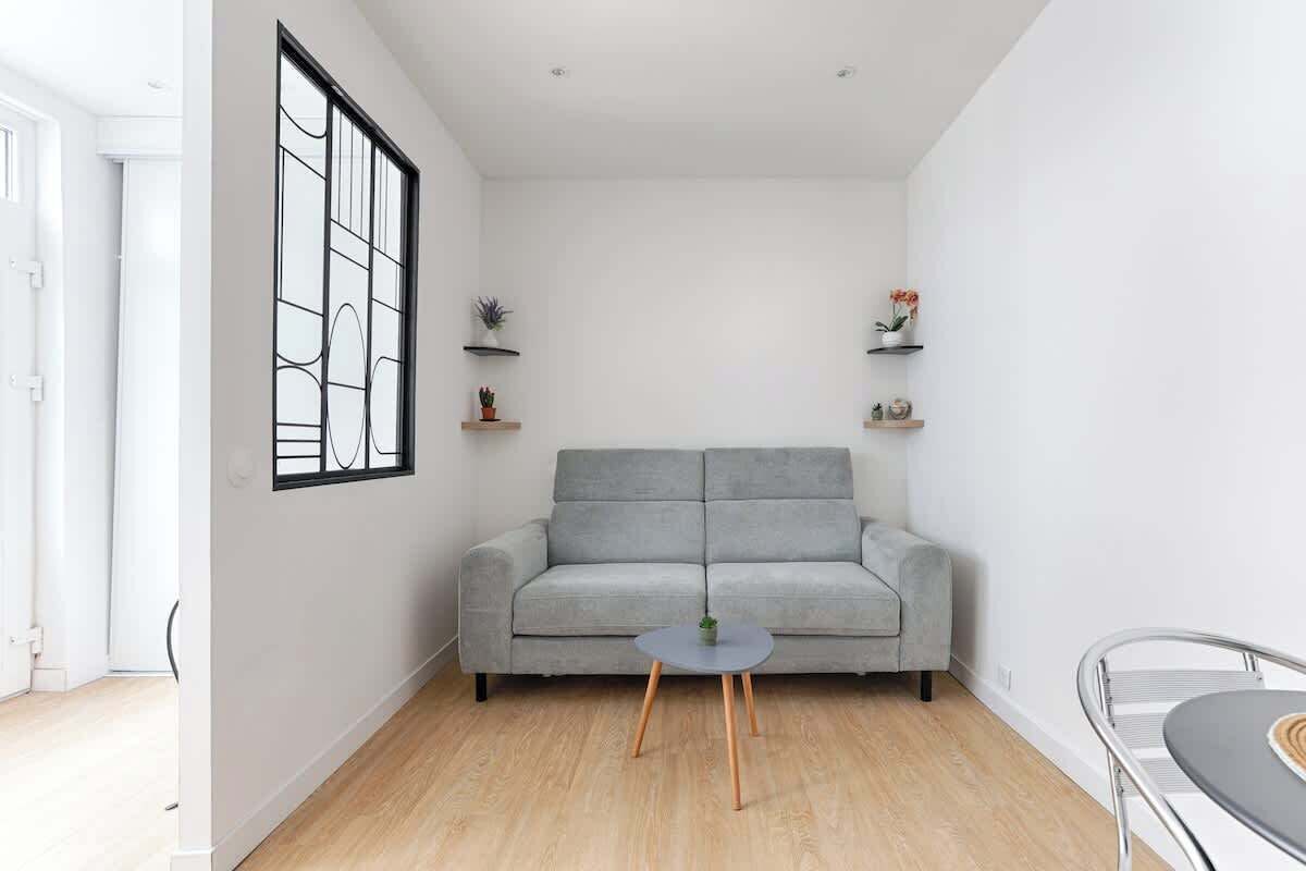 A modern living room with a grey sofa, a round coffee table, and two shelves with decorative items.