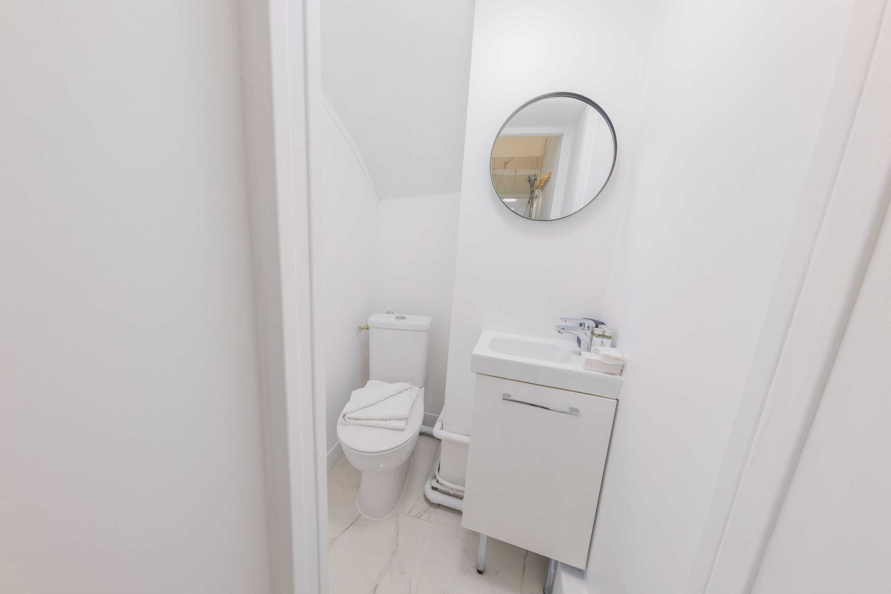 Un bagno piccolo e pulito con il water, un lavandino e uno specchio.