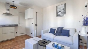 Een moderne woonkamer met een bank, een salontafel en een keukenhoek met kasten en een fornuis.