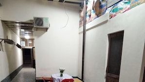A corridor with a tiled floor, a small table with chairs, and a door with a screen. - Caravan Hostel (Tashkent)