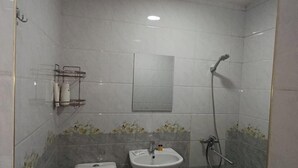 A small bathroom with a toilet, sink, and shower. - Caravan Hostel (Tashkent)