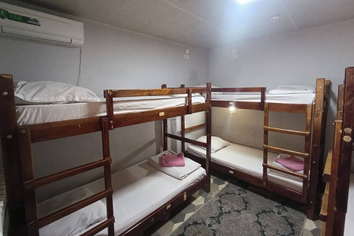 A bunk room with wooden bunk beds, a patterned rug, and a ceiling light.