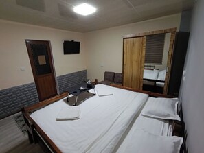 Een hotelkamer met een groot bed, een bureau, een stoel, een kledingkast en een televisie.