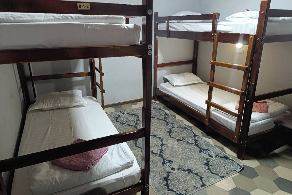 A room with bunk beds, a patterned rug, and a visible door handle.