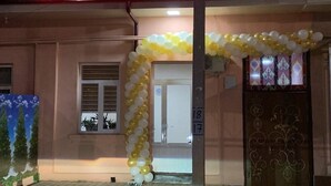 A caravan hotel with a neon sign, a decorative arch of balloons, and a gated entrance. - Caravan Hostel (Tashkent)