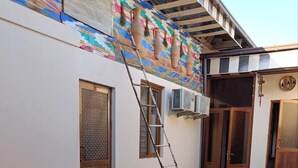 A courtyard with a paved walkway, a wooden table with red chairs, and a ladder leaning against a wall. - Caravan Hostel (Tashkent)