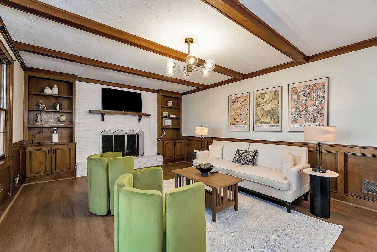 A living room with a fireplace, green chairs, a white sofa, and artwork on the wall.