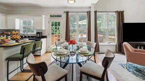 A modern kitchen with a dining area, large windows, and a flat-screen TV. - Chic Metro Family Stay / High Ceiling / Game Room (Lawrenceville)