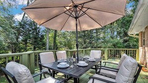 An outdoor dining area with a table set for four, surrounded by chairs, under a large umbrella. - ALL Kings!/ Gameroom/ Huge Deck/ Family Friendly (Norcross)