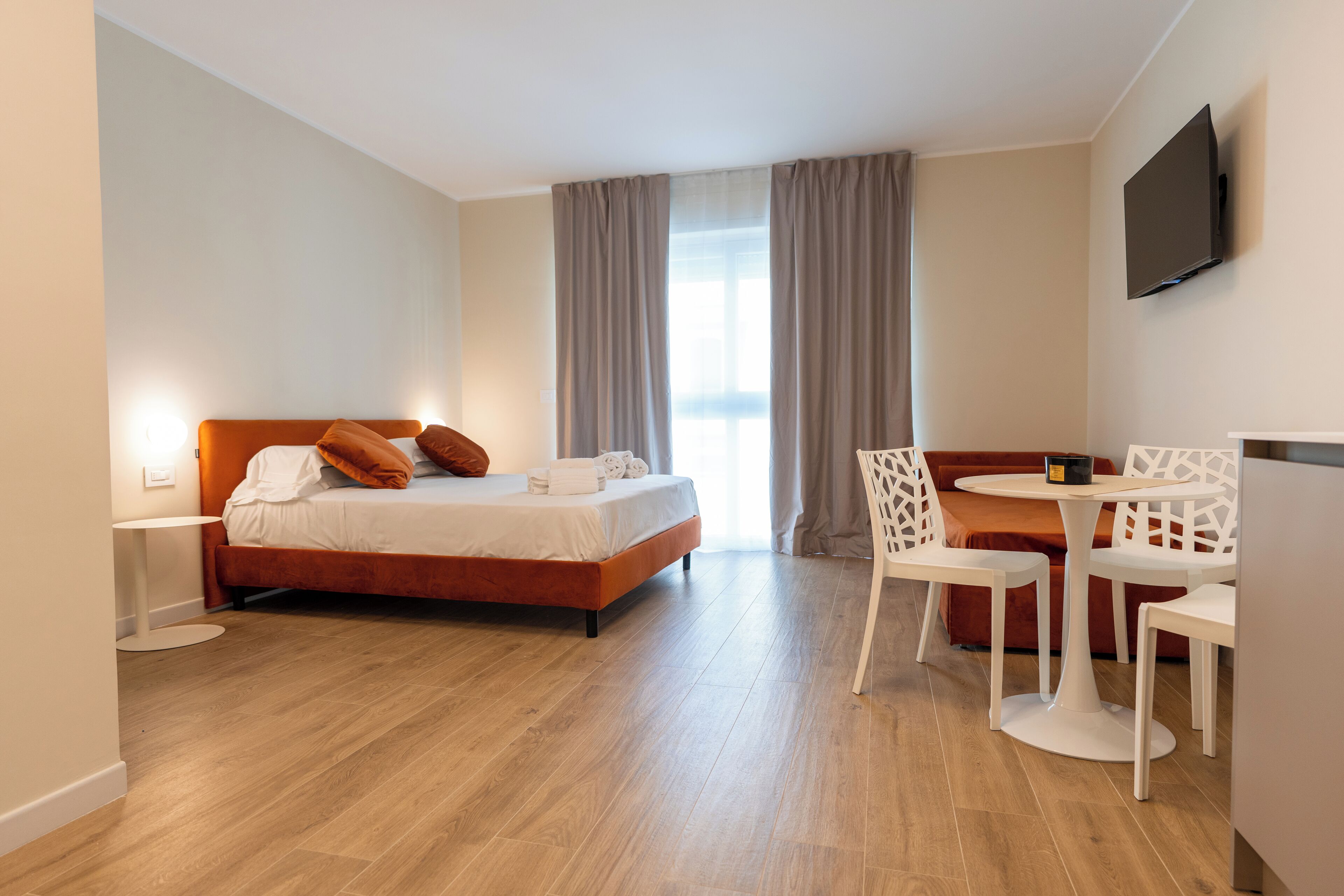 A modern hotel room with a bed, a small round table, and a TV.
