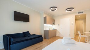 Et moderne hotelværelse med sovesofa, fladskærms-tv, tekøkken og spiseplads.