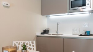 Et moderne køkken med mikrobølgeovn, vask og et lille spiseområde med bord og stole.