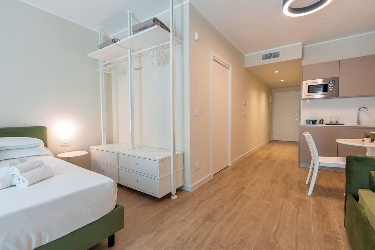 A modern hotel room with a bed, bedside table, and a built-in wardrobe.