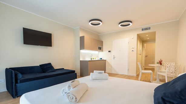 Et moderne hotelværelse med seng, sofa, fjernsyn og tekøkken.