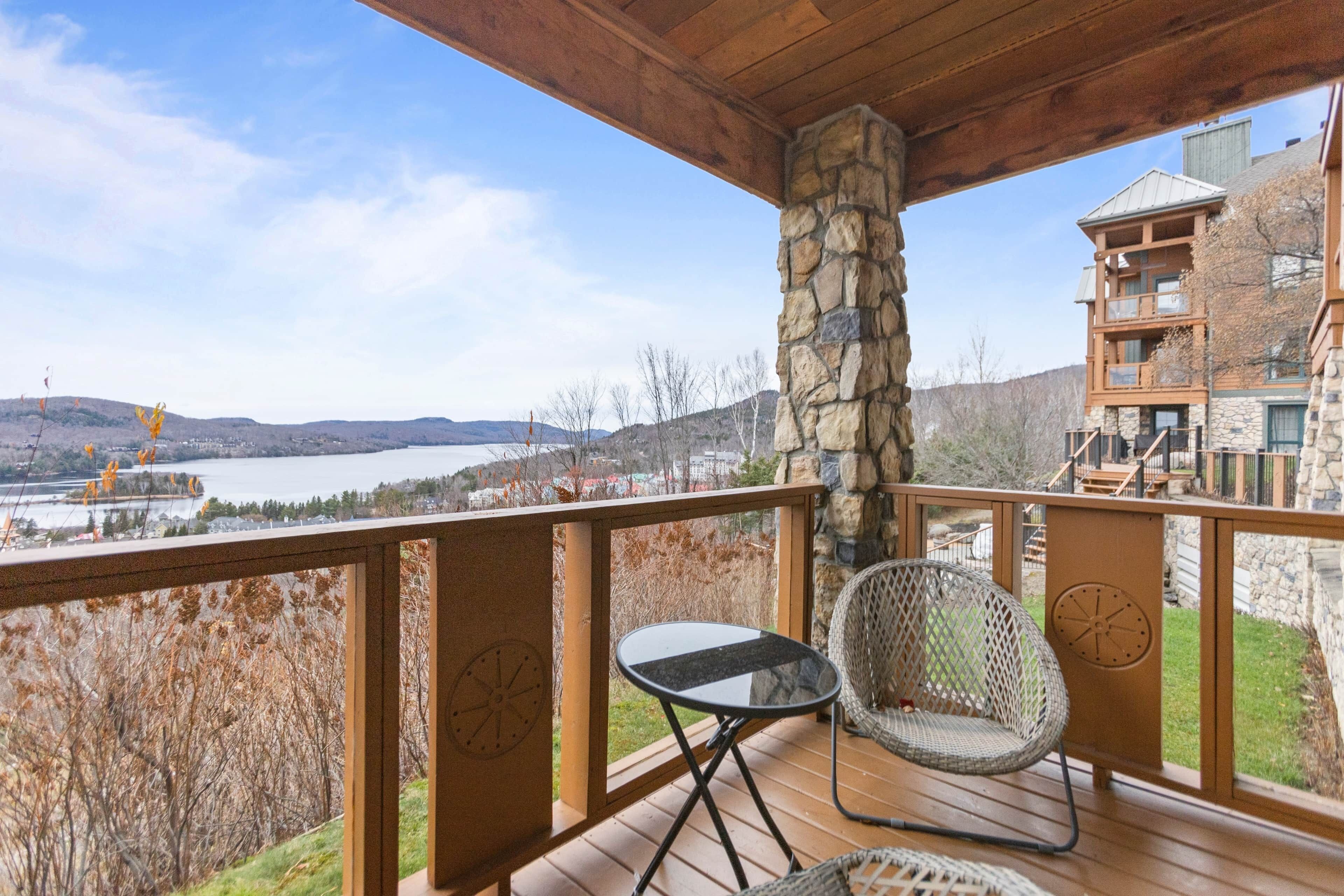 A wooden deck with a stone pillar, a small table, and a wicker chair.
