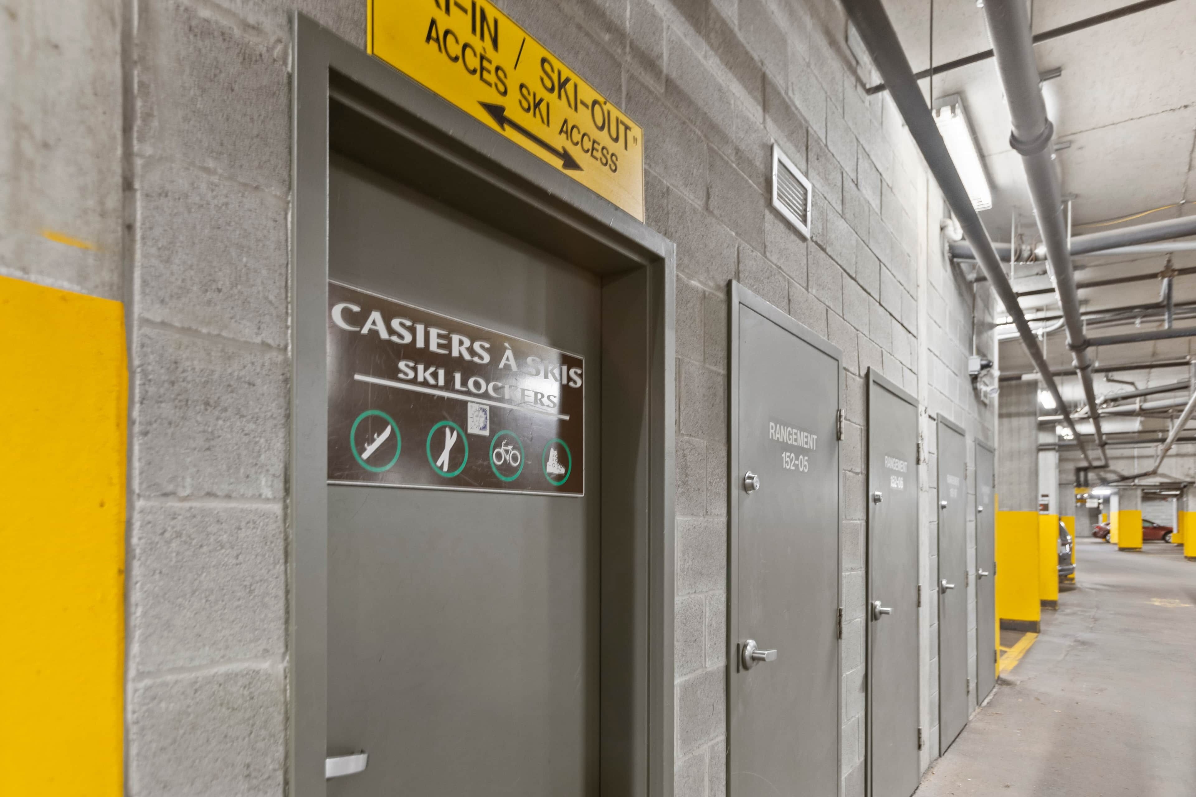 A ski locker room with a sign indicating ski-in/ski-out access and lockers for skis, snowboards, and bicycles.