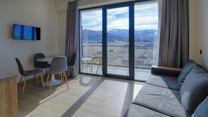 Een moderne woonkamer met een bank, een eettafel, stoelen en een televisie.