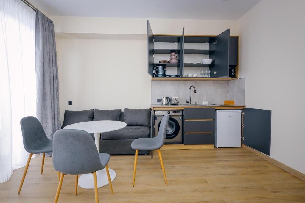 Um espaço compacto com cozinha compacta, área de refeições com mesa redonda e cadeiras, e máquina de lavar roupa.
