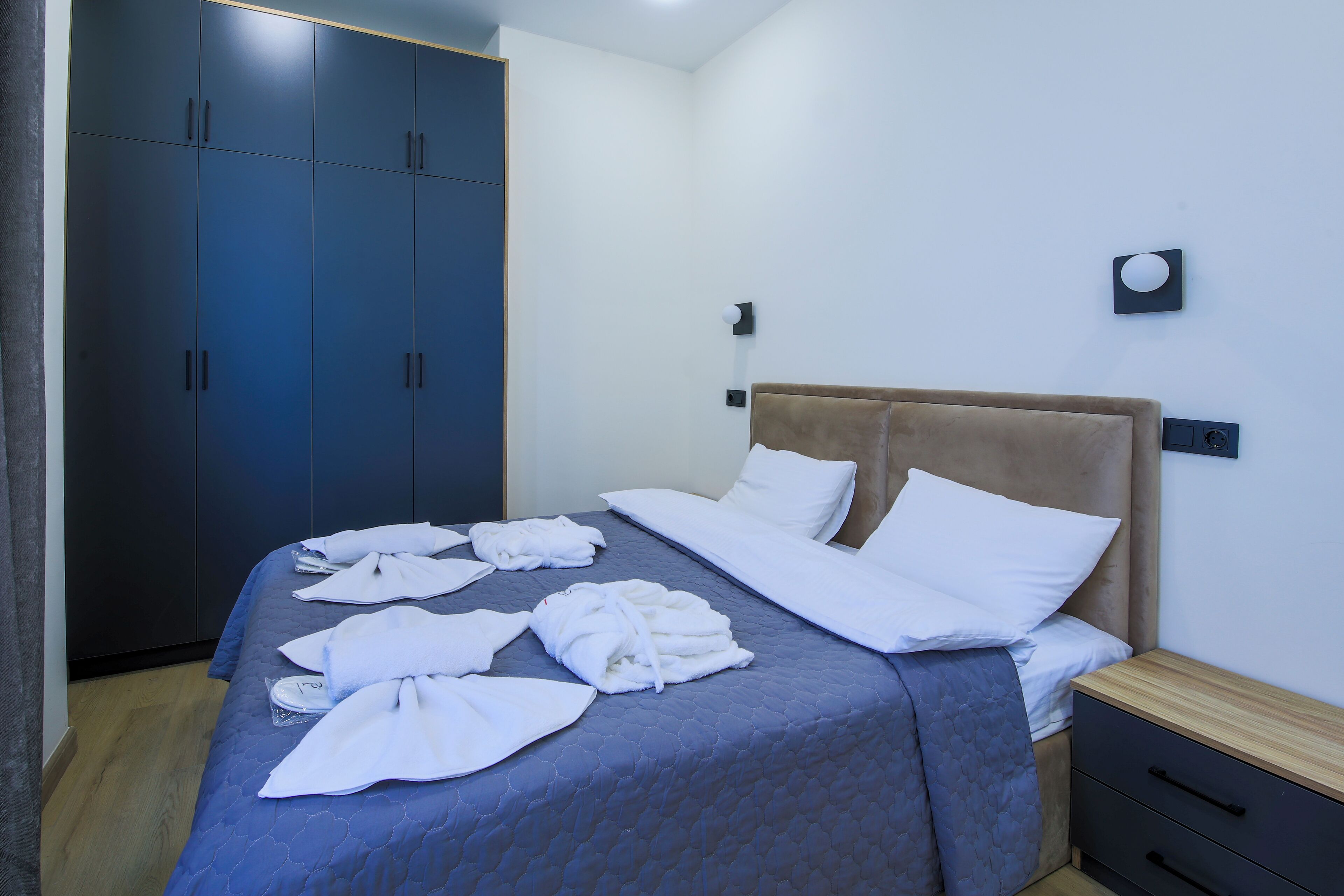 Una habitación de hotel con una cama, un armario y una mesita de noche.
