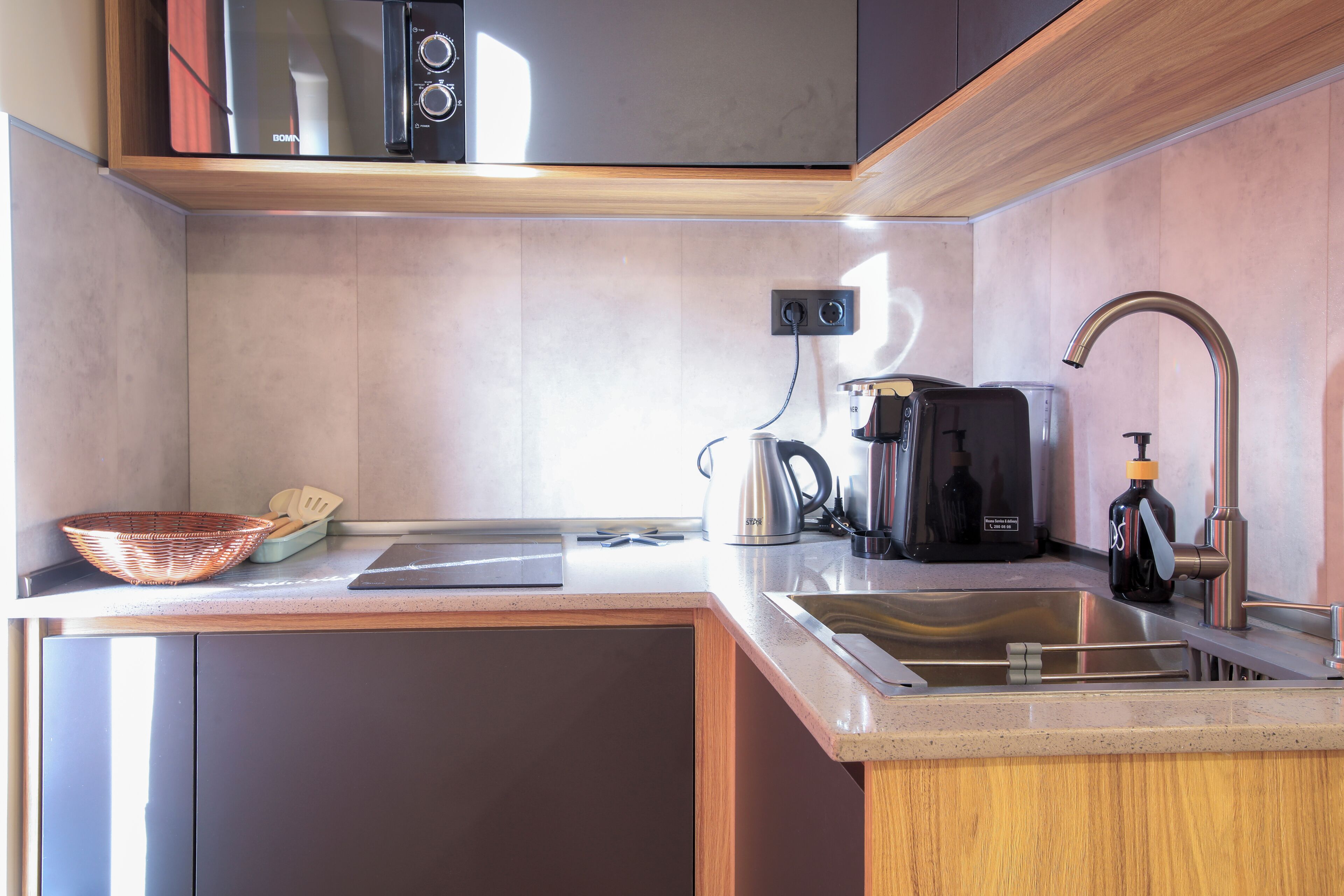A modern kitchen with a stainless steel sink, a kettle, and a coffee maker.