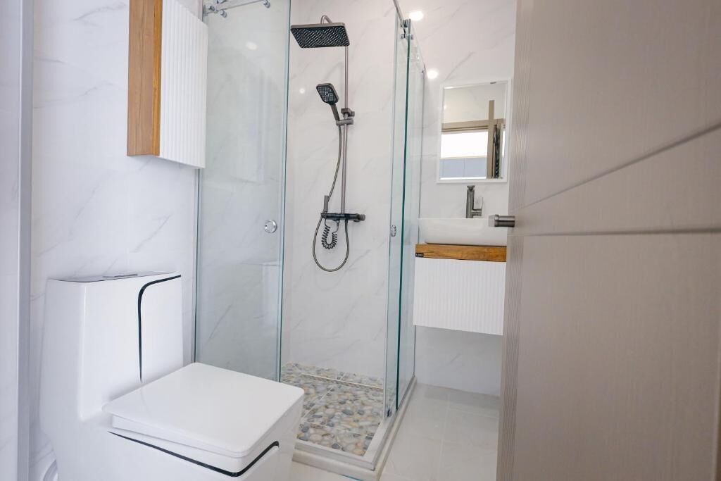 Une salle de bain moderne avec une douche à parois de verre, des toilettes blanches et un meuble-lavabo en bois.
