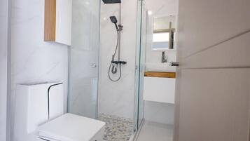 Une salle de bain moderne avec une douche à parois de verre, des toilettes blanches et un meuble-lavabo en bois.