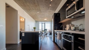Una cocina moderna con una isla central, electrodomésticos de acero inoxidable y vistas al exterior.