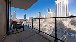 Un balcón con vista a un paisaje urbano, incluyendo edificios altos y un estacionamiento.