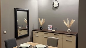 A dining area with a wooden table, black chairs, a mirror, a clock, and decorative plants. - Aetheria apartment (Shkupi)