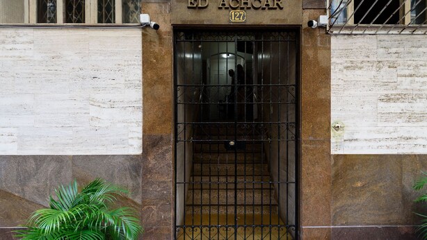 Entrada de un edificio con una reja metálica y una planta en maceta.