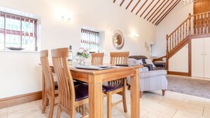 Zona pranzo con tavolo e sedie in legno, un lampadario e una scala che conduce a un livello superiore.