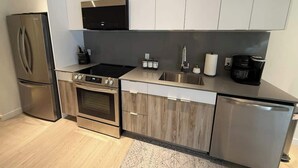 A modern kitchen with stainless steel appliances, a built-in oven, a microwave, and a coffee maker. - Bright, warm & spacious 1 BR in North End Halifax (Halifax)