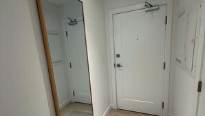A hallway with a large mirror, a white door, and a small closet with a towel rack. - Bright, warm & spacious 1 BR in North End Halifax (Halifax)