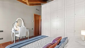 Een slaapkamer met een bed, een bureau met stoel, een spiegel en een kledingkast.