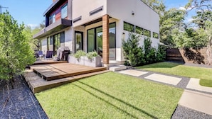 Een modern herenhuis met een terras, buitenmeubels en een verzorgd gazon.