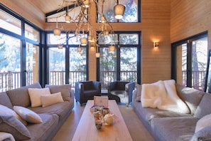 A cozy interior with a sofa set, a coffee table with tea cups, and a chandelier.
