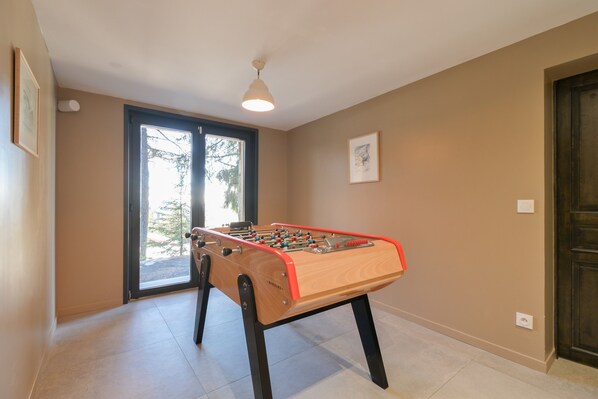 A room with a foosball table, a door, and a window.
