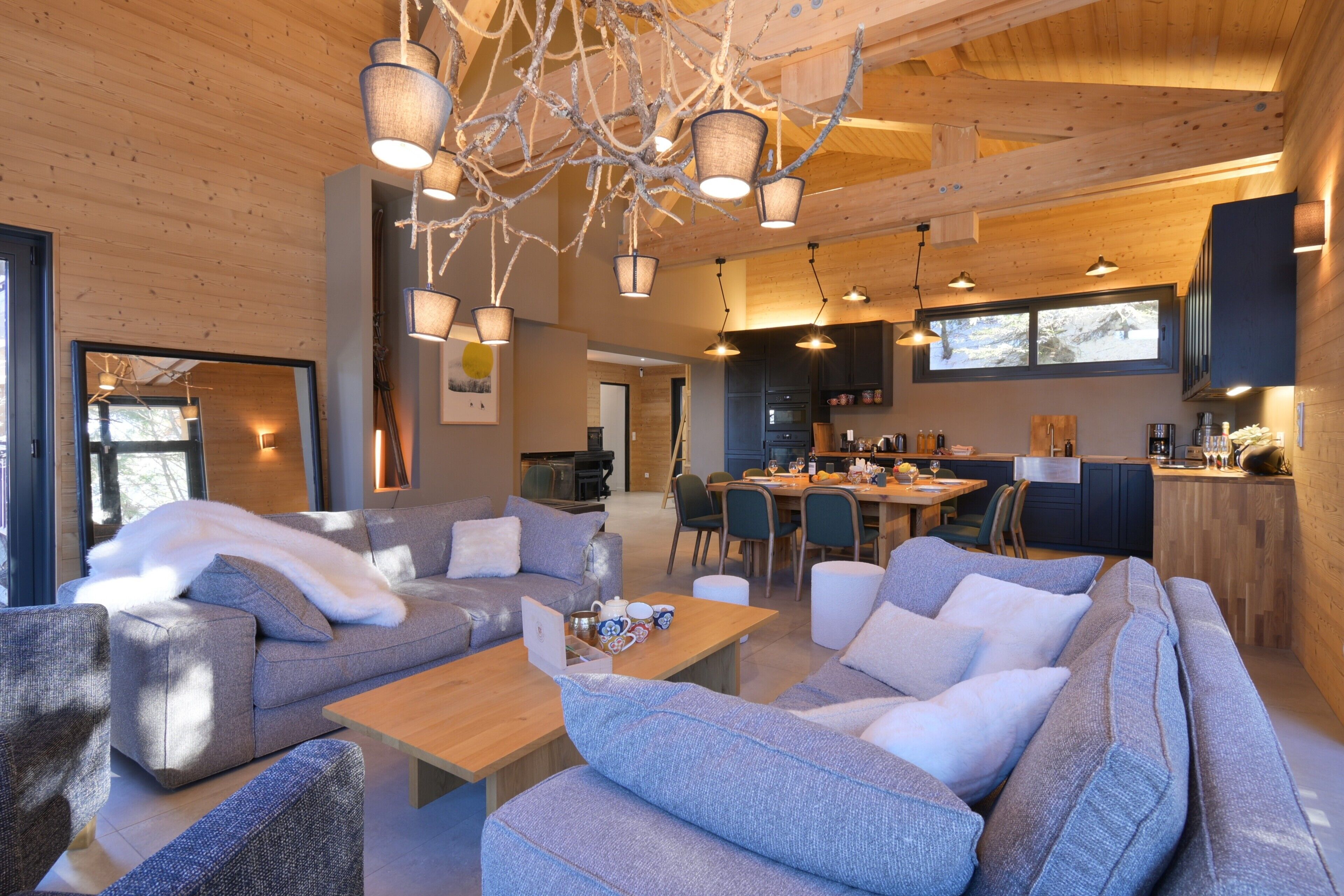 Un interior moderno con un conjunto de sofás, techo de madera y una zona de comedor.